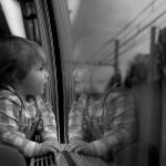 Photo noir et blanc de Eric Corec, représentant un enfant dans un wagon de train regardant par la fenêtre.